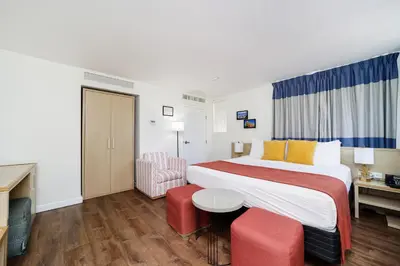 a hotel room with a large bed and red chairs at Villa Italia by At Mine Hospitality in Miami Beach