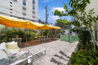 a patio with a couch and a yellow umbrella at Villa Italia by At Mine Hospitality in Miami Beach