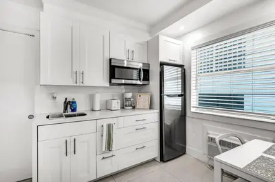 a kitchen with white cabinets and a black refrigerator at South of Fifth Oceanfront condo with Beach Perks! in Miami Beach