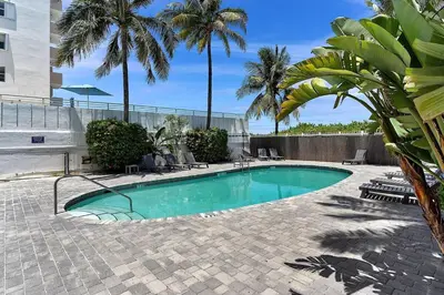 a swimming pool in a courtyard with palm trees at South of Fifth Oceanfront condo with Beach Perks! in Miami Beach