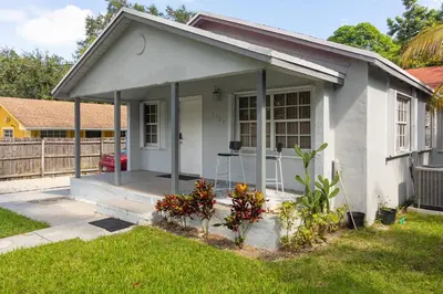 a small white house with a porch with flowers at Charming 3BR Getaway - Central Miami Location in Miami