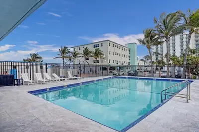 a swimming pool with chairs and a building at Charming Beachside Studio - Steps to the Beach in Hollywood
