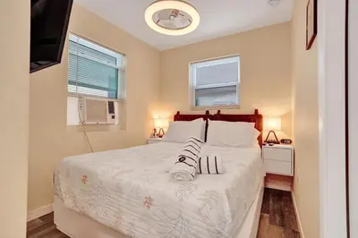 a bedroom with a large white bed with two windows at Charming Beachside Studio - Steps to the Beach in Hollywood