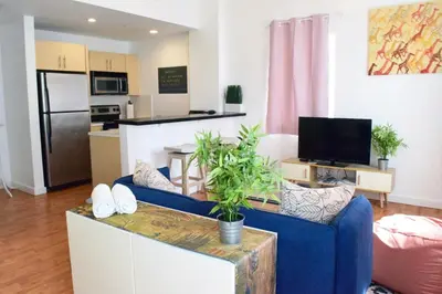 a living room with a blue couch and a kitchen at Light-Filled Apt Steps to Beach Convention Center in Miami Beach