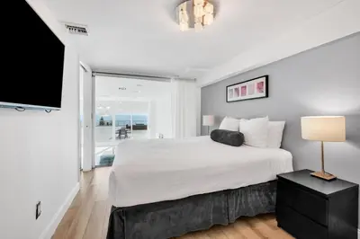 a white bedroom with a large bed and a flat screen tv at Shine Suites Balcony Duplex 11 in Miami Beach