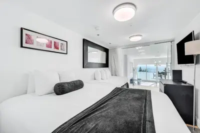a white bedroom with two beds and a television at Shine Suites Balcony Duplex 11 in Miami Beach
