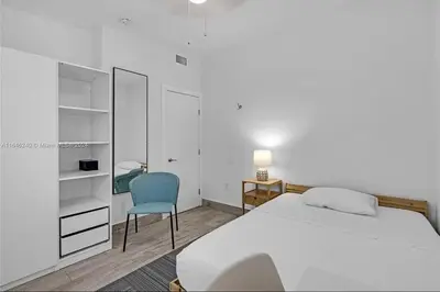a bedroom with a white bed and a blue chair at Avocado House in Miami