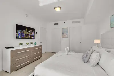 a white bedroom with a large bed and a dresser at Icon Brickell Retreat 1BR and Spa, Pool, Views in Miami