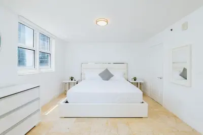 a white bedroom with a white bed and two windows at Bright and Cozy 2 Bedroom in Miami