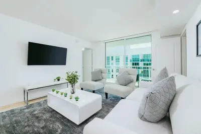 a living room with white furniture and a flat screen tv at Bright and Cozy 2 Bedroom in Miami