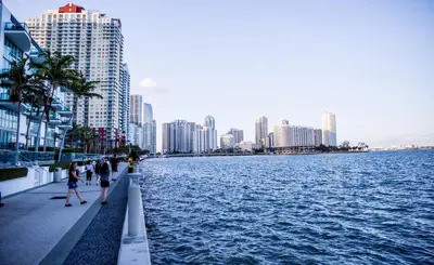 people walking on a sidewalk next to a body of water at 2bedroom ocean views brickell free parking in Miami