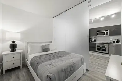 a white bedroom with a bed and a kitchen at Luxurious 2Bedroom Apt Parking in Brickell. in Miami