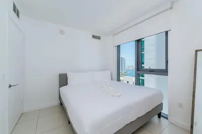 a white bedroom with a bed and a large window at Exclusive, Amazing, Bright and Spacious at Brickell in Miami