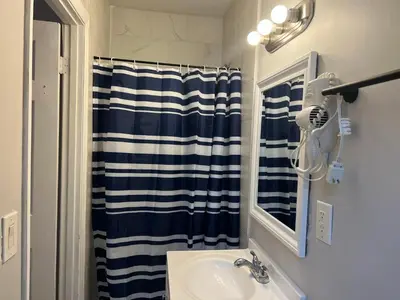 a bathroom with a sink and a blue and white shower curtain at Coral Gable 3BR House in Miami