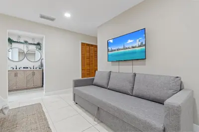 a living room with a couch and a tv on a wall at 6BR 3BA Heated Pool Miami Vacation in Miami