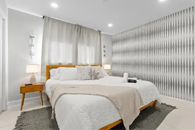 a white bedroom with a large bed and a window at 6BR 3BA Heated Pool Miami Vacation in Miami