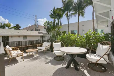 a patio with a table and chairs and palm trees at The Firefly in Miami Beach
