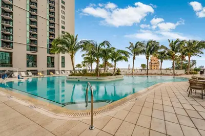 a swimming pool with palm trees and a building at Bellini Breeze - Cozy Central Miami Pool and Gym in Miami