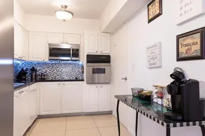 a kitchen with white cabinets and a black counter top at Beachfront 2 BR Apartment full Kitchen- Sian in Hollywood