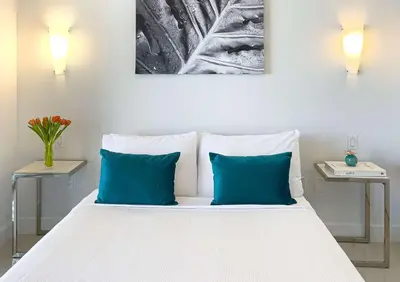 a white bed with two blue pillows and two tables at MVR - Magnificent Bay & River Views SPA Balcony in Miami