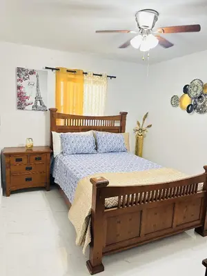 a bedroom with a wooden bed and a ceiling fan at Miami Casa in Miami Gardens