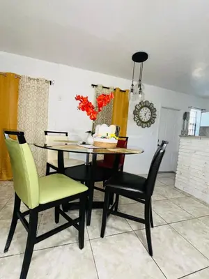 a dining room table with green chairs and a table and chairsktop at Miami Casa in Miami Gardens
