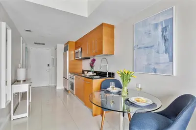 a kitchen with a glass table and blue chairs at MVR Sleek Condo with Iconic Views in Miami