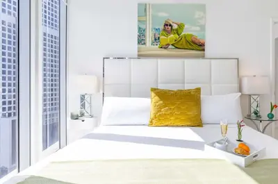 a bedroom with a white bed and a painting on the wall at MVR - Sky-High Style in Brickell in Miami
