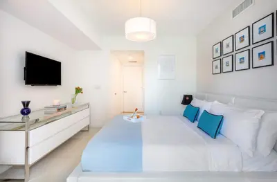 a white bedroom with a bed and a tv at MVR - Sky-High Style in Brickell in Miami
