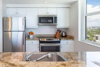 a kitchen with white cabinets and a stainless steel refrigerator at MVR-Tired of Hotels This Stay Breaks the Mold in Miami