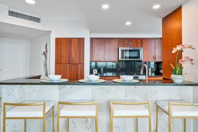 a kitchen with a marble counter top and wooden cabinets at MVR - Where Families and Professionals Align in Miami