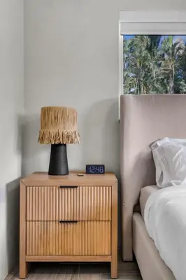 a nightstand with a lamp on it next to a bed at 4BR Biscayne River Home with Pool & Pickleball Fun in Biscayne Gardens