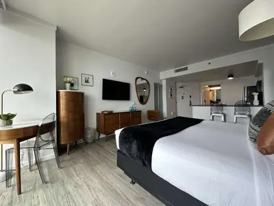 a hotel room with a bed and a desk and a table at MVR-Balcony Apartments Filling Up-Act Now in Miami