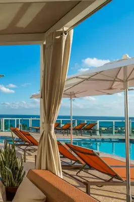 a pool with chairs and umbrellas next to the ocean at MVR - Elevate Your Stay with Stunning Ocean Views in Miami