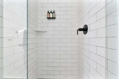 a white tiled shower with three bottles on a shelf at MVR - Sunset & Skyline Magic from Your Balcony in Miami