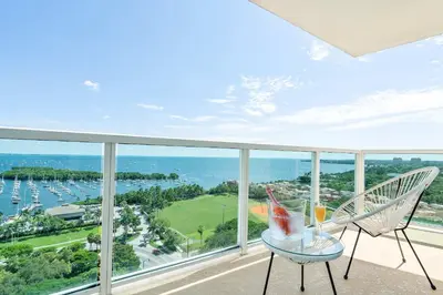 a balcony with two chairs and a table with a drink on it at MVR - Skyline Dreams from Your Private Balcony in Miami