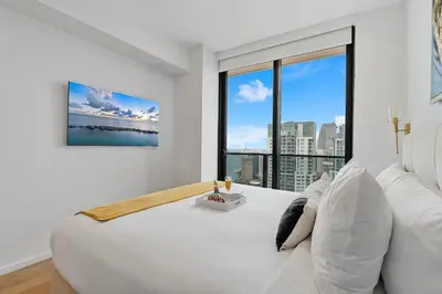 a white bedroom with a large bed and a large window at MVR - VIP Pool Deck & Rooftop Lounge Access in Miami