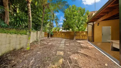 a backyard with a fence and trees and a building at Luxury Queen Room, Walk to UM, Free Car Service! in Miami