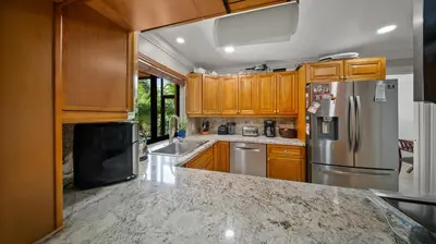 a kitchen with wooden cabinets and a stainless steel refrigerator at Luxury Queen Room, Free Car Service, Walk to UM! in Miami