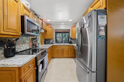 a kitchen with wooden cabinets and a stainless steel refrigerator at Large Private Room, Free Car Service, Walk to UM! in Miami