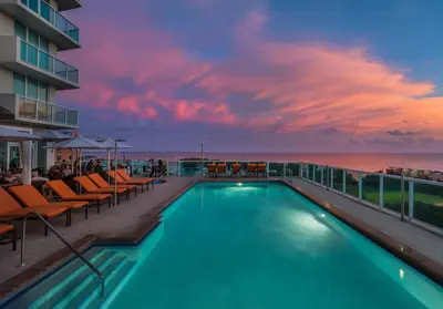 a swimming pool on the roof of a building with a sunset at MVR King Suite Room Bay View in Miami