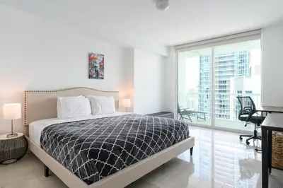a white bedroom with a bed and a large window at Spacious Penthouse in Brickell 3 BR, Free Parking in Miami