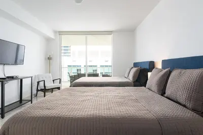 a bedroom with two beds and a couch and a television at Spacious Penthouse in Brickell 3 BR, Free Parking in Miami