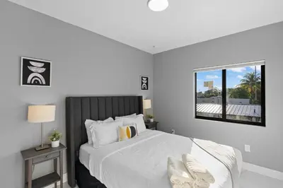 a white bedroom with a large bed with a window at Amazing Townhouse w Free Parking in Miami