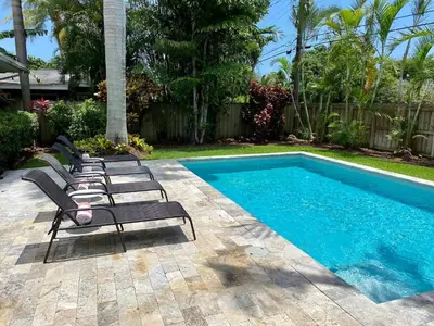 a row of lounge chairs next to a swimming pool at Chic Fort Lauderdale Getaway w/Private Heated Pool in Fort Lauderdale