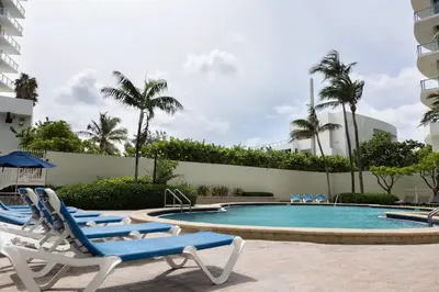 a swimming pool with lounge chairs next to a building at Beachfront 2 BR Apt Full Kitchen - No Resort Fee in Hollywood