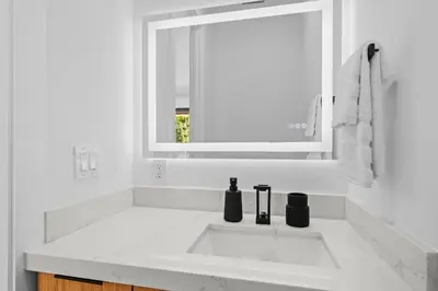 a white bathroom with a sink and a mirror at Modern Zen Oasis in Design District Sleeps 16 in Miami