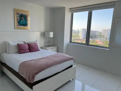 a bedroom with a bed with purple pillows and a window at Family Oriented Apartments with unbelievable views in Hallandale Beach