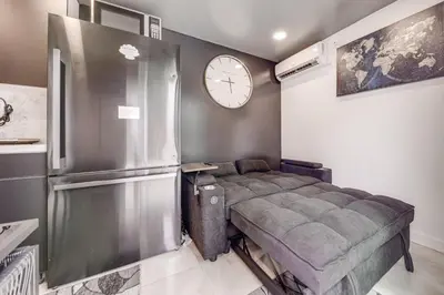 a bedroom with a refrigerator and a clock on the wall at Mod Bungalow with Ultra-Private Outdoor Hang Space! in Miami Gardens