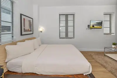 a large white bed in a room with windows at Steps from the Ocean Comfy Studio with King Bed in Miami Beach